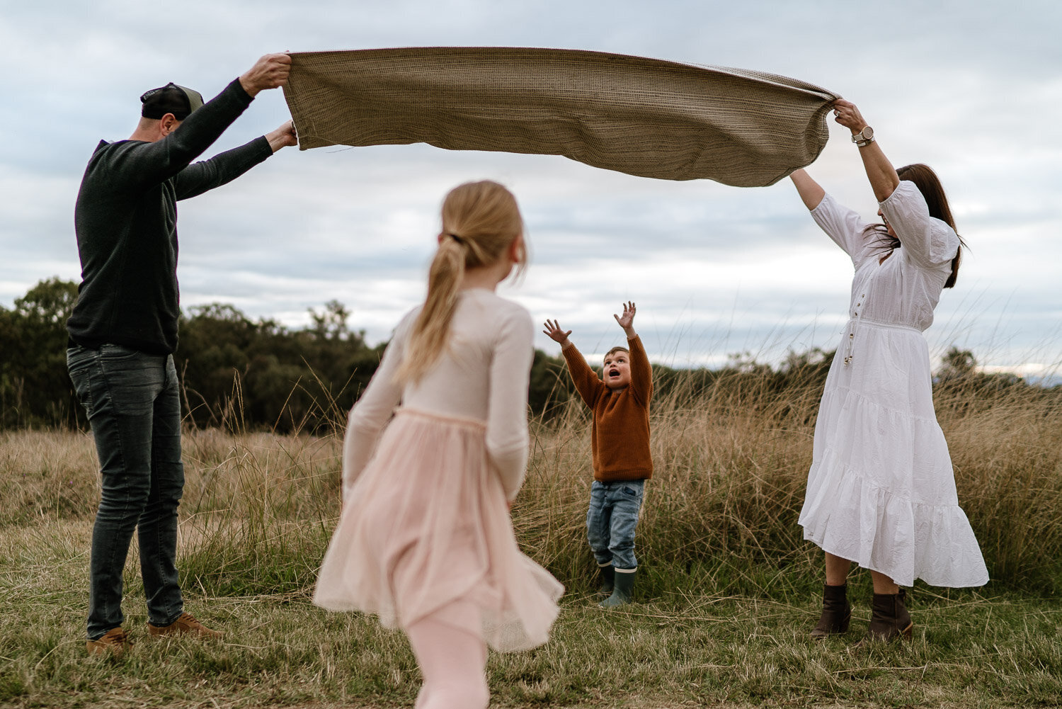 Family playing together in an open field during a Sydney family photography session