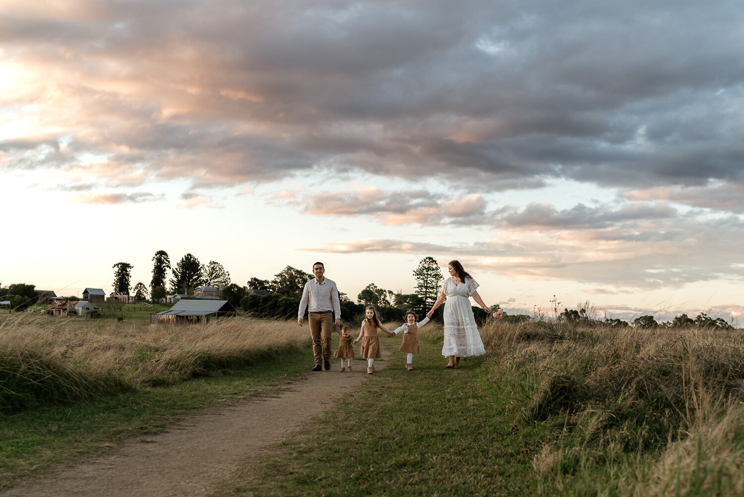 Family walking a country path beneath a dramatic sky during a Sydney family photography session