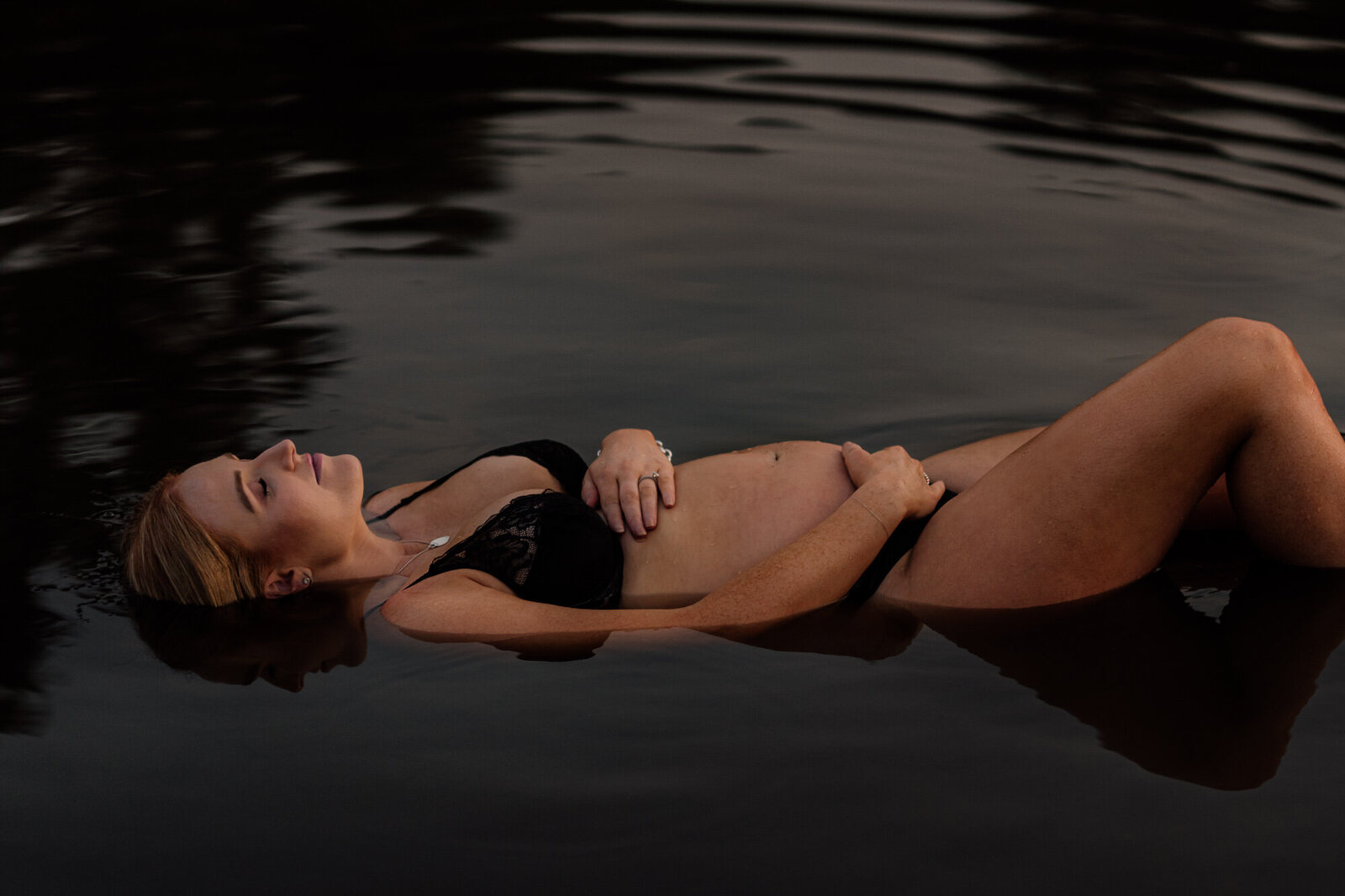 Expecting mother floating in still water at dusk during a Sydney maternity session