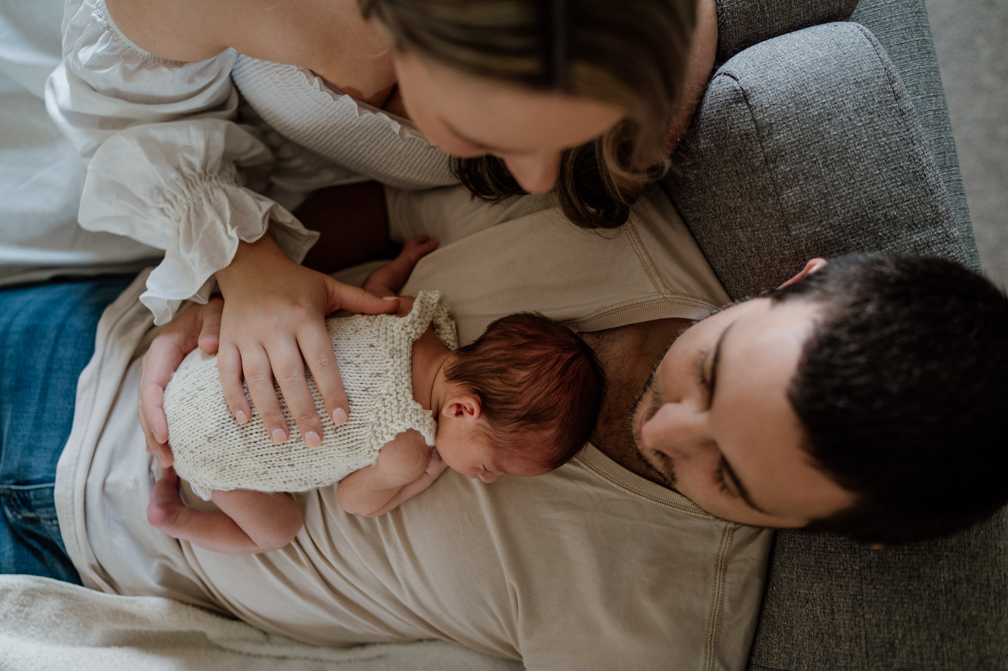 New family together in an open field at sunset with their newborn